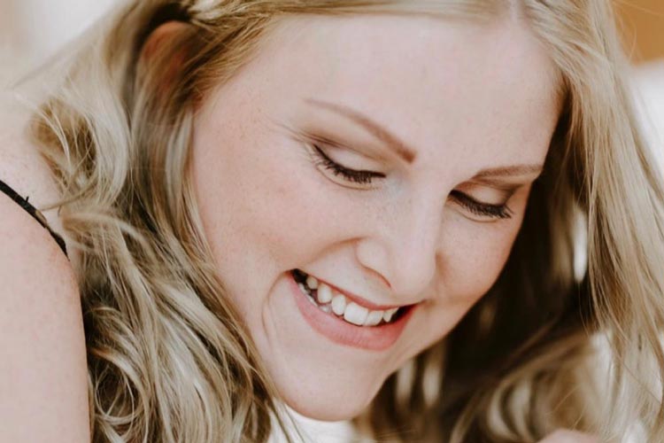Kvinna som ler efter hon blivit sminkad